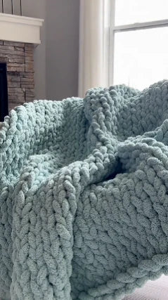 A handmade chunky chenille blanket draped over an armchair